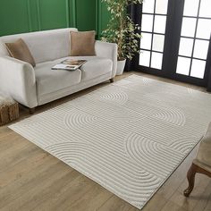 a living room with green walls and a white rug on the floor next to a couch