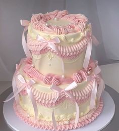 a three tiered cake with pink and white icing on the top, sitting on a plate