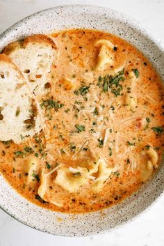 a white bowl filled with soup and some slices of bread on top of the bowl