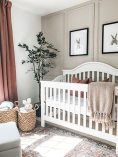 a baby's room with a white crib and two pictures on the wall