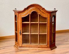 an old wooden bookcase with glass doors on the front and bottom shelves is sitting on a hard wood floor