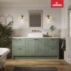 a bathroom with green cabinetry and white sink, bathtub and mirror on the wall