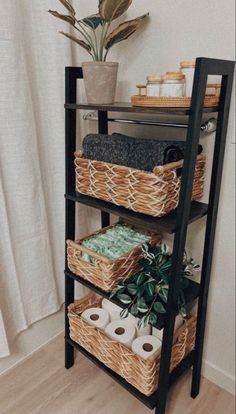 a shelf with baskets and toilet paper on it next to a potted houseplant