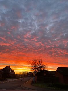 the sky is red and orange as the sun sets in the distance behind some houses