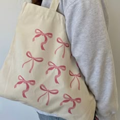 a woman is holding a bag with pink bows on it