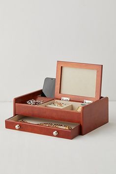 an open wooden jewelry box on a white surface