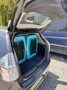 the back end of a car with two large blue crates in it's trunk