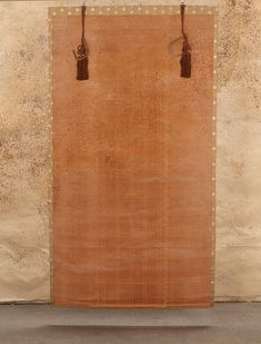 a large brown piece of cloth hanging on a wall next to a wooden pole with two hooks