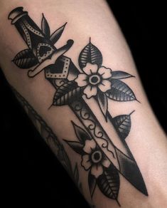 a black and white photo of a cross with flowers on the side of his leg