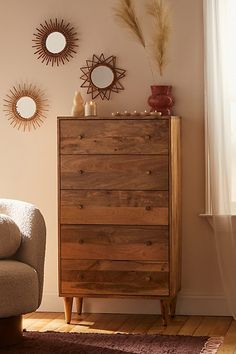 a living room scene with focus on the chest of drawers and mirror wall hangings