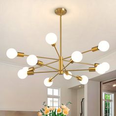 a chandelier hanging from the ceiling in a dining room with white walls and flooring