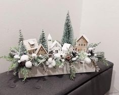 christmas decorations on top of a mantle in front of a white wall with snow and evergreens