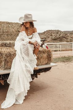 a woman sitting on the back of a pick up truck in front of hay bales