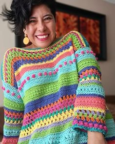 a woman wearing a multicolored crocheted sweater and smiling at the camera