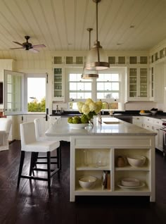 a kitchen with white cabinets and an island in the middle, surrounded by wooden flooring