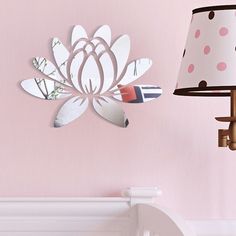 there is a pink wall with a flower on it and a lamp next to it