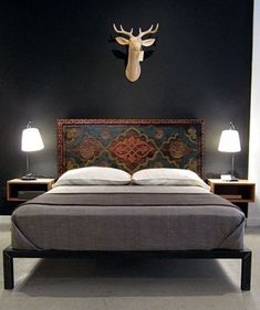 a bed with a deer head mounted on the wall above it and two lamps next to it