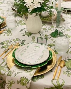 the table is set with green and white plates, silverware, and vases