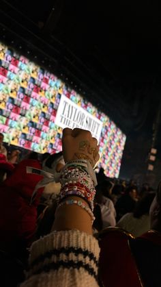 a person's arm with bracelets on it in front of a large screen