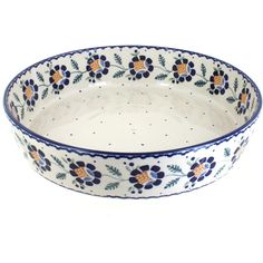 a blue and white bowl with flowers on the rim, sitting in front of a white background