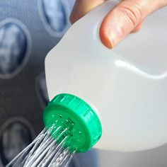 a hand is sprinkling water from a plastic bottle with a green cap on it