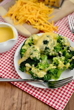 broccoli covered in cheese on a plate next to a bowl of gravy