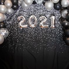 balloons and streamers decorate the backdrop for a new year's eve celebration in black, silver and white