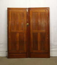 two wooden doors are open against a white wall