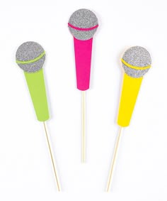 three different colored sticks with glitter tops on them and one has a yellow stick sticking out of it