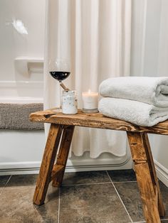 a wooden table topped with two white towels and a candle next to a bath tub