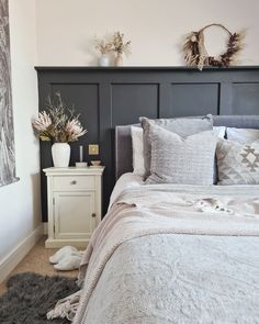 a white bed sitting in a bedroom next to a night stand with flowers on it