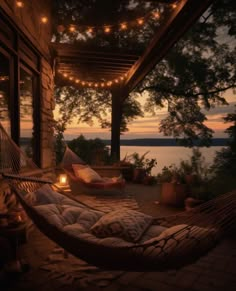 a hammock with pillows and lights on the porch