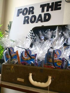 a suitcase filled with candy sitting on top of a table next to a sign that says for the road