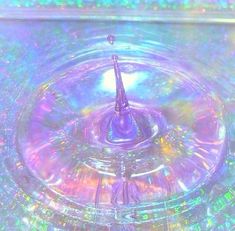 a close up of a water drop in a glass bowl with iridescents