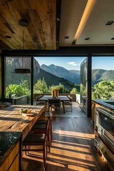 an open kitchen and dining area with mountains in the backgrounnd, surrounded by wood flooring