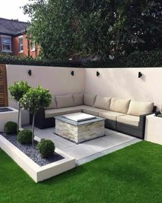 an outdoor living area with grass, couches and potted trees in the middle