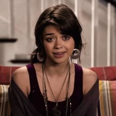 a woman sitting on top of a couch wearing necklaces and earring's