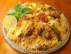 a plate full of rice and meat with lemon wedges on the side for garnish