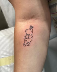 a small winnie the pooh tattoo on the right side of the arm is shown