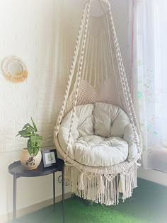 a hammock chair hanging from the ceiling next to a table with a potted plant on it