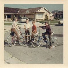 a group of people riding bikes down a street with houses in the backgroud