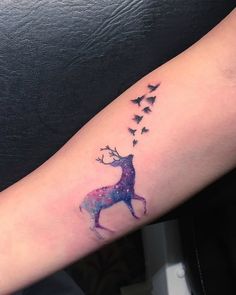 a tattoo on the arm of a woman with a deer and birds flying around it