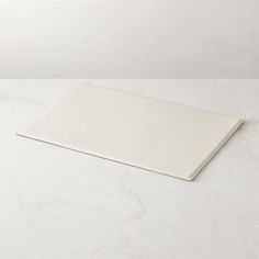 a white cutting board sitting on top of a marble counter next to a knife and fork