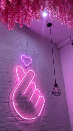 a pink neon sign hanging from the side of a brick wall next to a light fixture