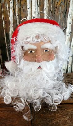 a santa claus with glasses and beard on top of a wooden table in front of birch trees