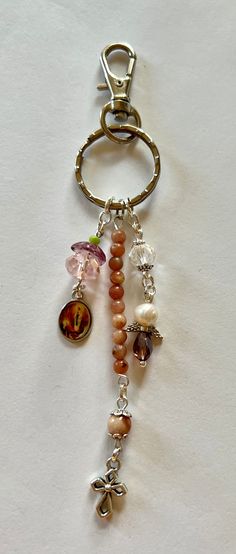 a keychain with charms attached to it on a white surface, including an orange and pink bead necklace