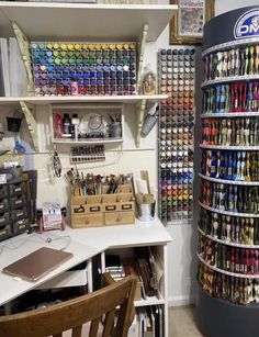 a room filled with lots of crafting supplies on shelves next to a computer desk