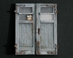 an old pair of wooden doors with glass inserts on the top and bottom, against a black background