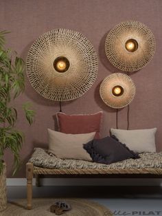 a bed with pillows and two lights on the headboard next to a potted plant