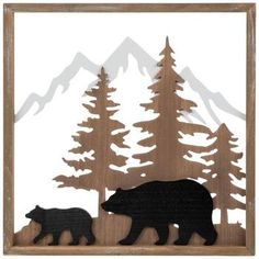 a bear and cub are standing in front of some trees with snow capped mountains behind them